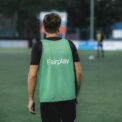 man in green and black adidas tank top and black pants standing on green grass field