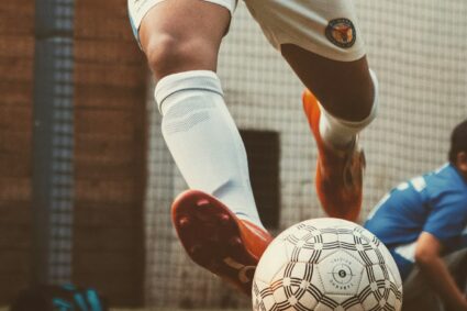 person in white and red soccer jersey kicking soccer ball