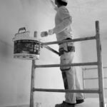 a man painting a wall with a paint roller